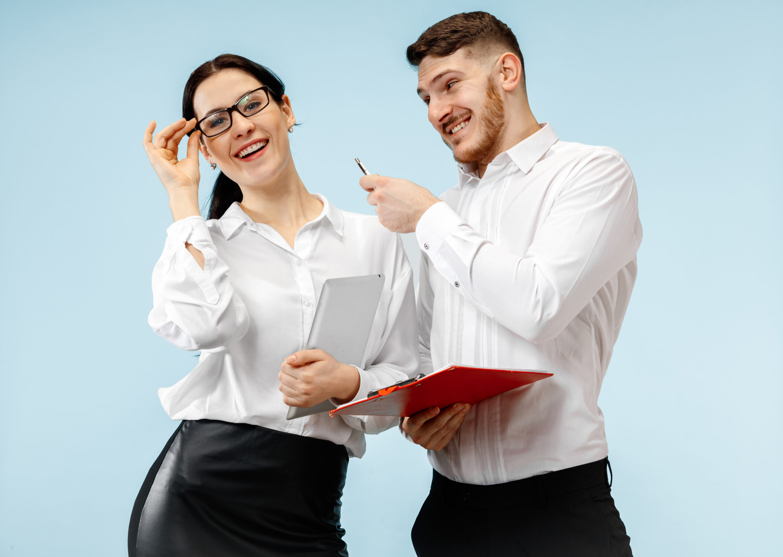 Concept of partnership in business. Young happy smiling man and woman standing against blue background at studio
